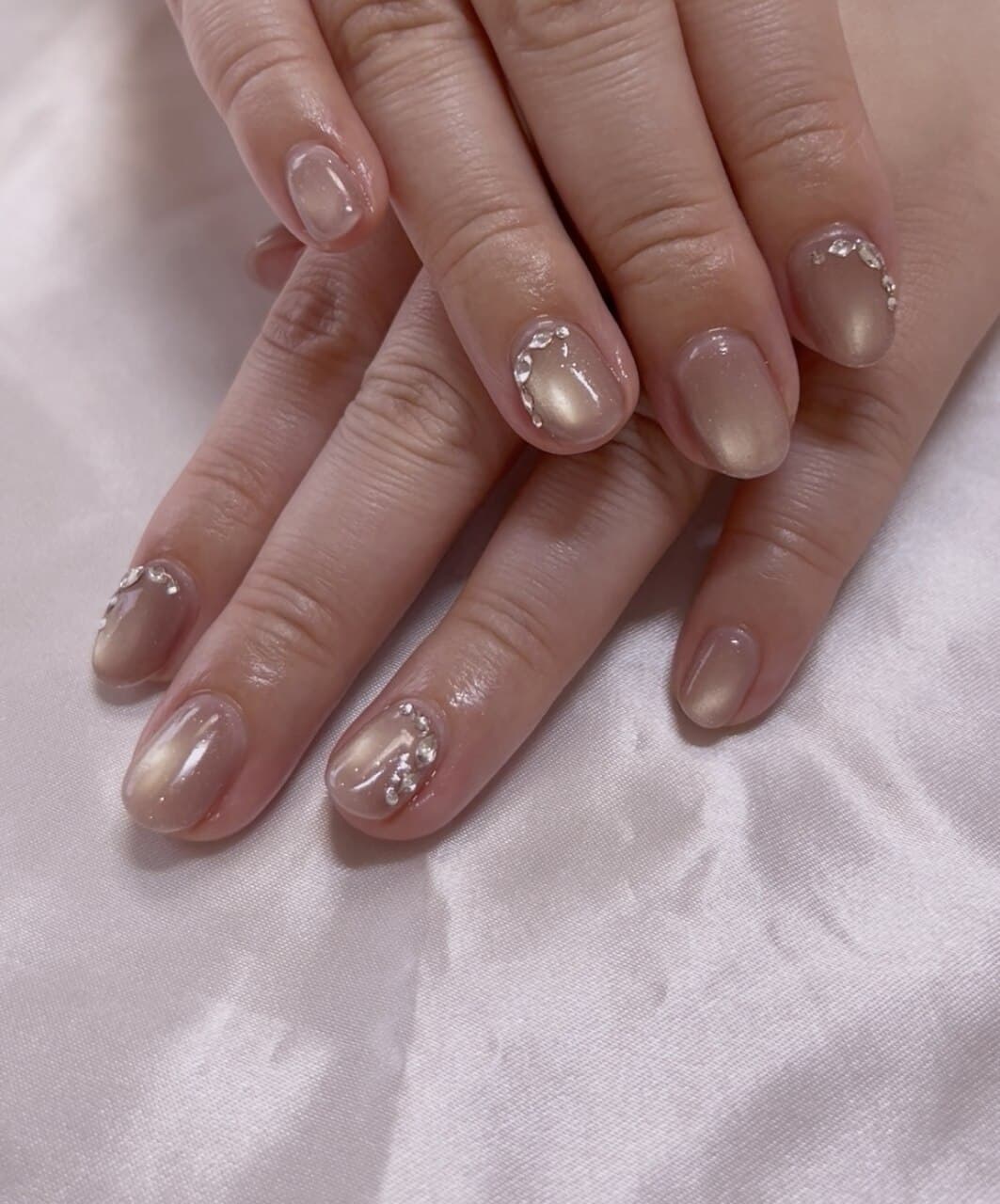 肌になじむベージュに柔らかな光とビジューを添えた、AURA NAILのハンドネイル